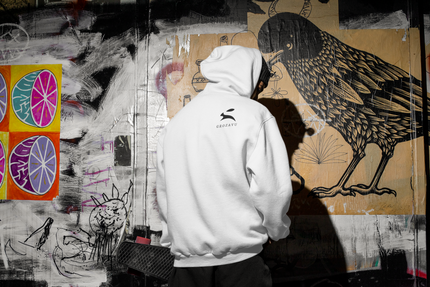 Grozavu men’s white premium cotton hoodie with back rabbit logo, urban graffiti wall scene, relaxed streetwear fit