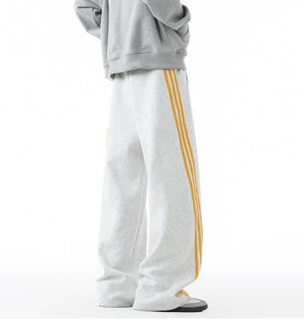Heavyweight Three-Stripe Pants - Loose Fit showcasing soft, structured fabric with sporty yellow stripe detailing.