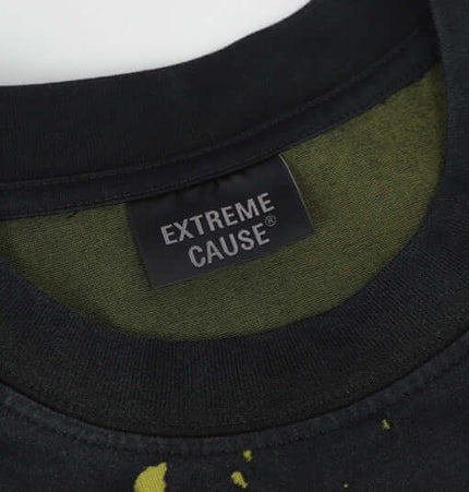 Close-up of the neckline of a black shirt featuring the EXTREME CAUSE® label and a splattered design.