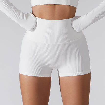 Woman wearing white high waist lift yoga shorts made from organic cotton blend, showcasing relaxed, ribbed fabric design for summer and spring.