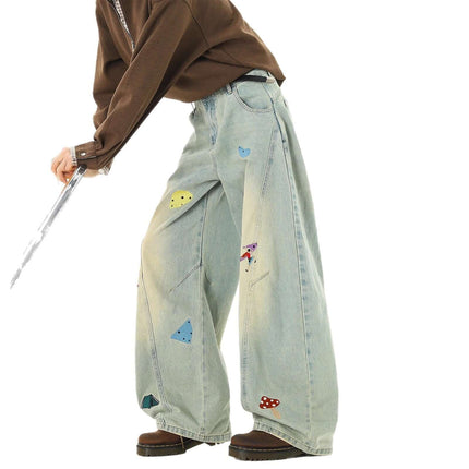 Person wearing Embroidered Patchwork Denim Pants with playful designs and a loose fit for streetwear style.