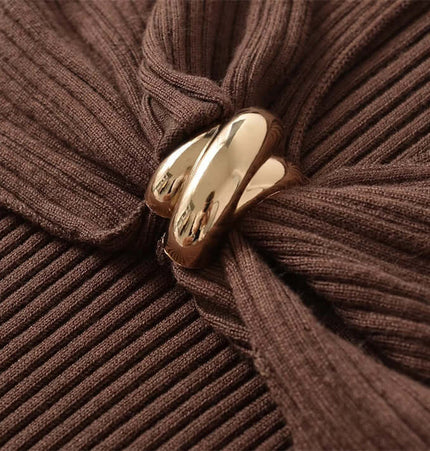 Close-up of the metal knot detail on the Metal Knot Hollow-Out Flare Sleeve Knit Top in brown.