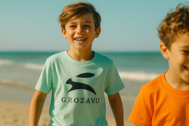 Two children on a beach with one wearing a Grozavu t-shirt.