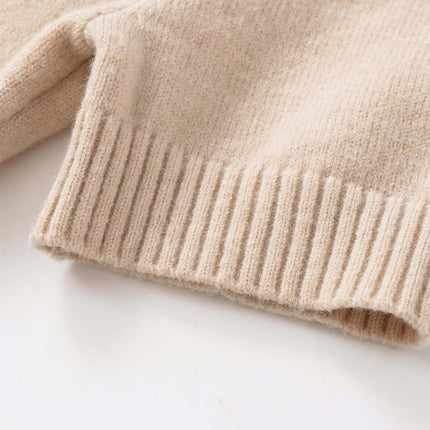 Detail view of the hem of the Round Neck Casual Knit Sweater, showcasing soft beige knit fabric.
