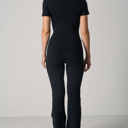 Back view of a woman wearing a Casual Fit Cotton Jersey Yoga Set, featuring a short sleeve crop top and high-waist long flare pants.