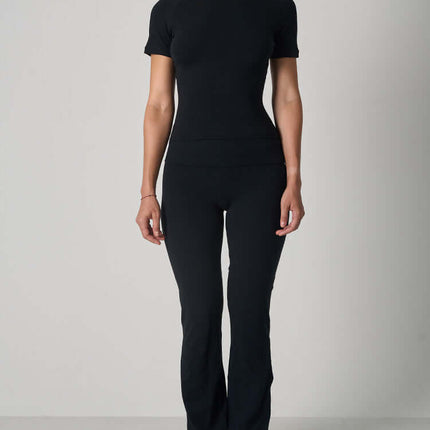 Casual Fit Cotton Jersey Yoga Set worn by a woman, showcasing a stylish black crop top and high-waist flare pants.