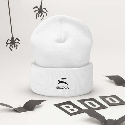 Cuffed Beanie displayed with Halloween decorations, showcasing a cozy white design with a logo.