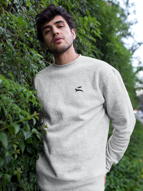 Man wearing Grozavu white sweater with bunny logo – minimalist streetwear fashion in natural outdoor setting