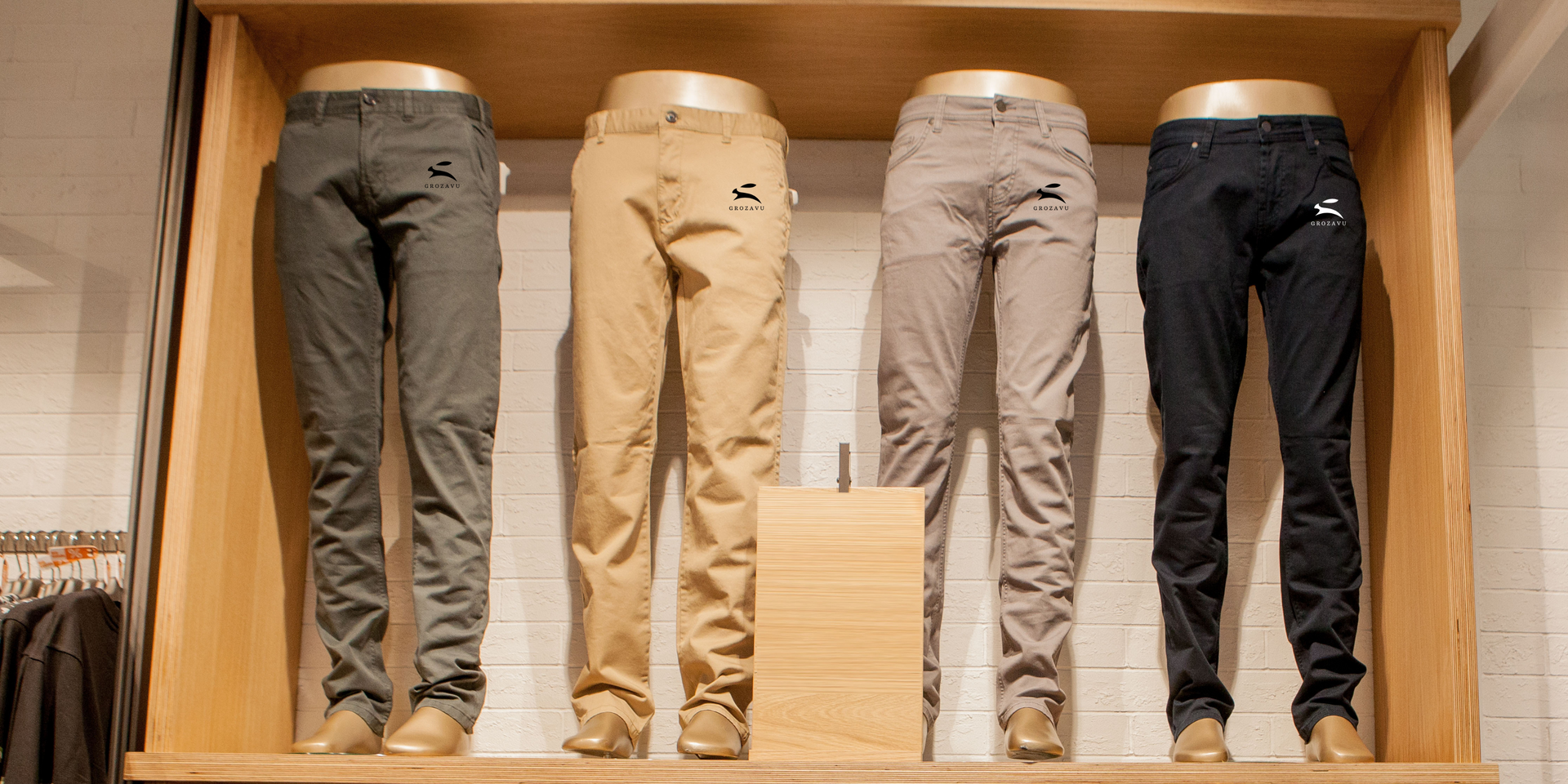 Four Grozavu men’s cotton chinos—olive, khaki, taupe and black—with rabbit logo at hip, slim-fit casual pants on store display