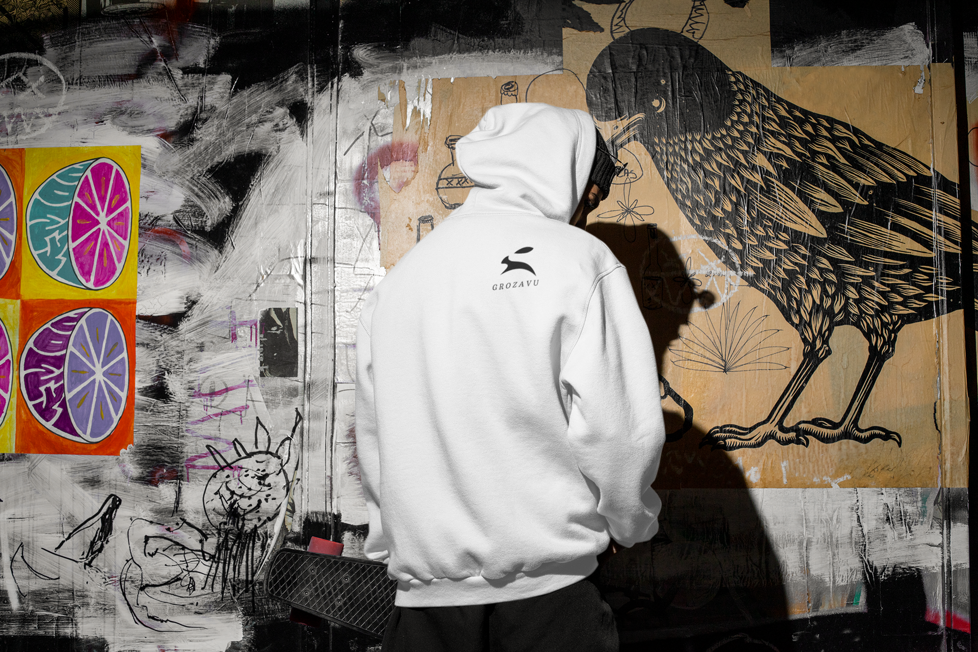 Grozavu men’s white premium cotton hoodie with back rabbit logo, urban graffiti wall scene, relaxed streetwear fit
