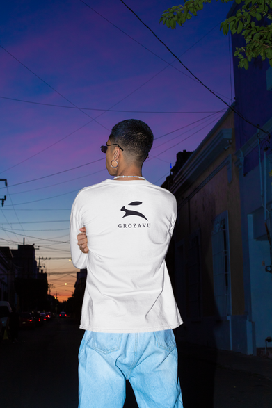 Back view of man wearing white Grozavu T-shirt with rabbit logo at sunset outdoors.