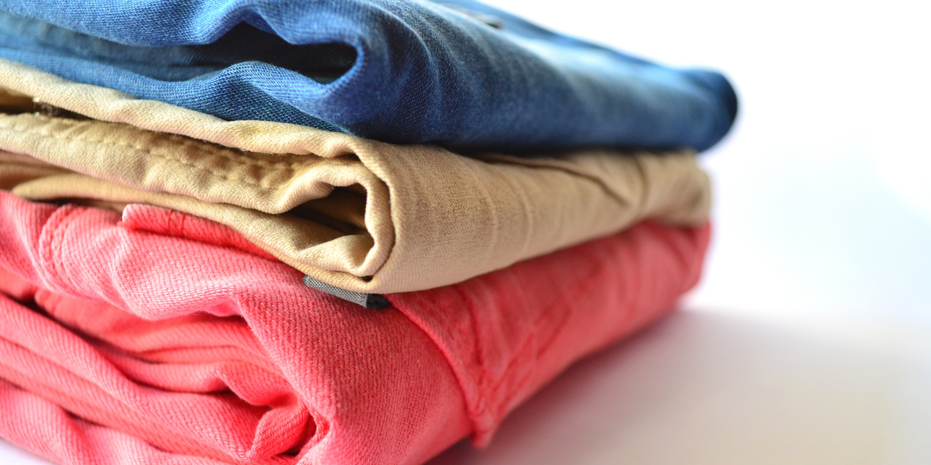 Stack of Grozavu premium cotton apparel in blue, beige, and coral, showing soft, breathable fabric texture for daily comfort