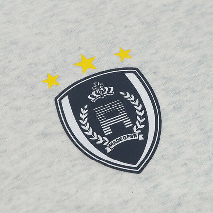 Logo patch on an oversized hooded sweatshirt featuring stars and a shield design.