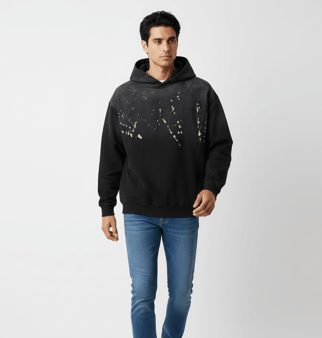 Man wearing a Splashing Ink Spliced Hooded Sweatshirt with a unique splashing ink design.